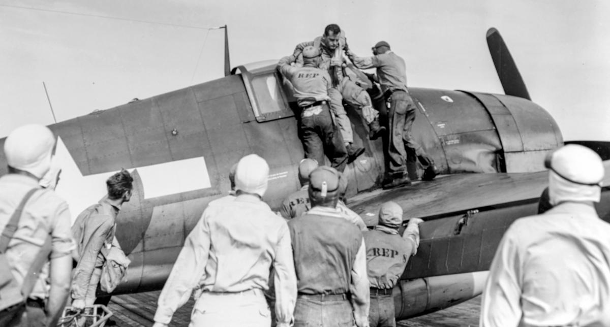 Wounded pilot being pulled out of a Hellcat on board USS Essex (CV-9)