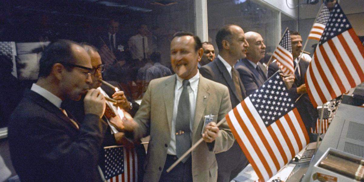 NASA and Manned Spacecraft Center officials and flight controllers light cigars to celebrate the conclusion of the Apollo 11 mission.