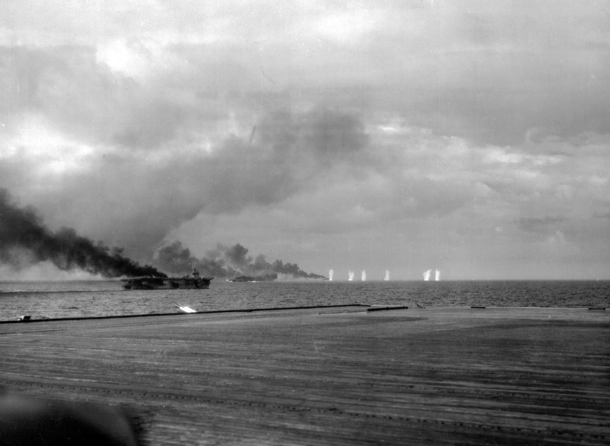 The carrier St. Lo (far left) and several other vessels make smoke as they attempt to evade the Japanese shells raining down on them during the Battle of Samar