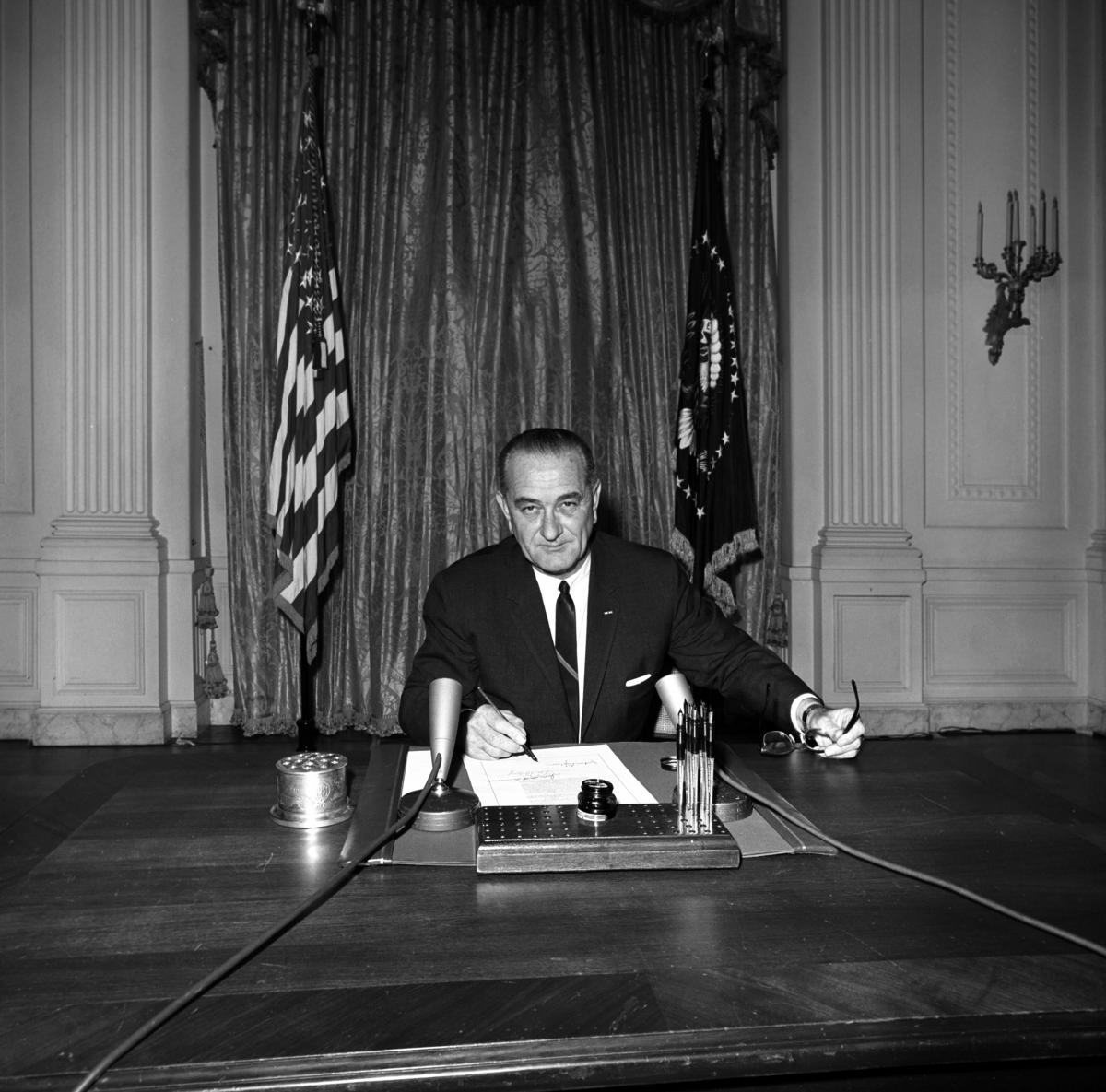 President Lydon Baines Johnson sitting at a desk in the White House