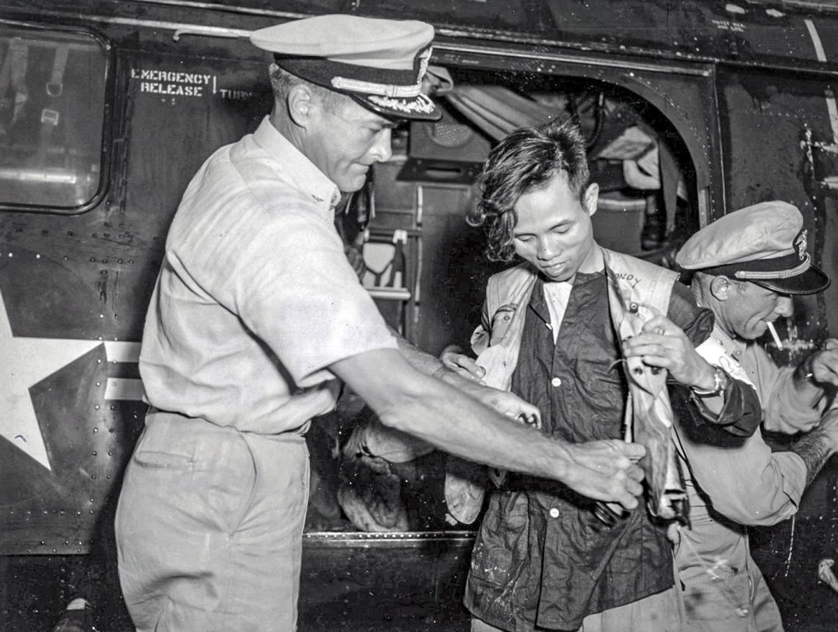  Captain Winn helps a Vietnamese prepare for the helicopter flight to the USS Estes (AGC-12).