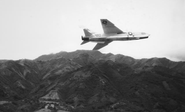An RF-8A Crusader photo reconnaissance plane of Light Photographic Squadron 63 (VFP-63) flies over the mountainous terrain of Indochina.