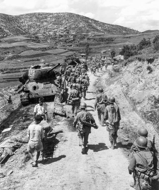  Marines file past knocked-out North Korean T-34 tanks During their defense of the Pusan perimeter on 18 August 1950