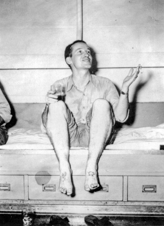 Chief Warrant Officer Cecil S. King, Jr. sitting on a bunk with a drink in hand