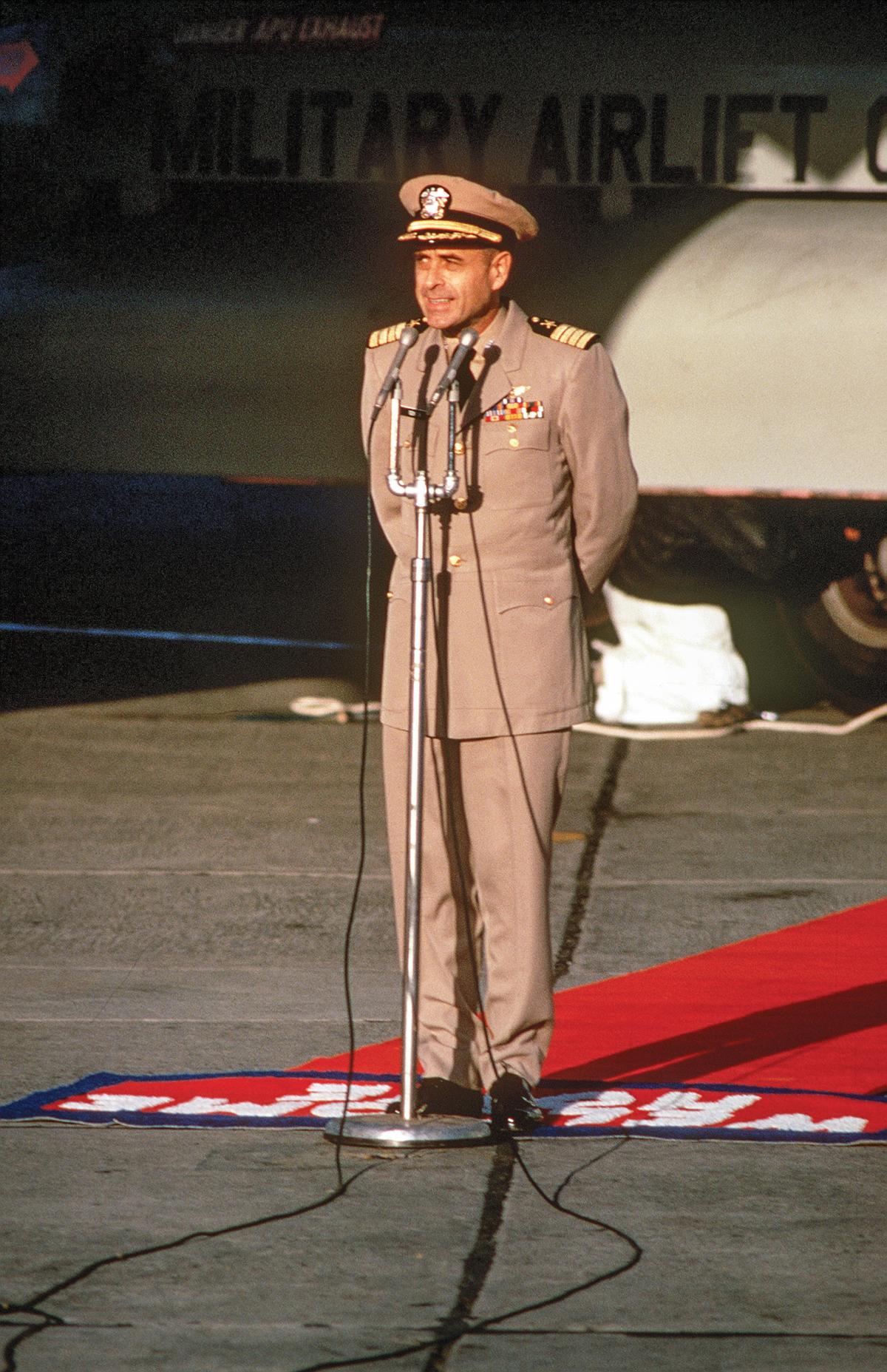 Captain Jeremiah Denton delivering remarks at Clark Air Base, Philippines, in February 1973 in front of a C-141 Starlifter aircraft