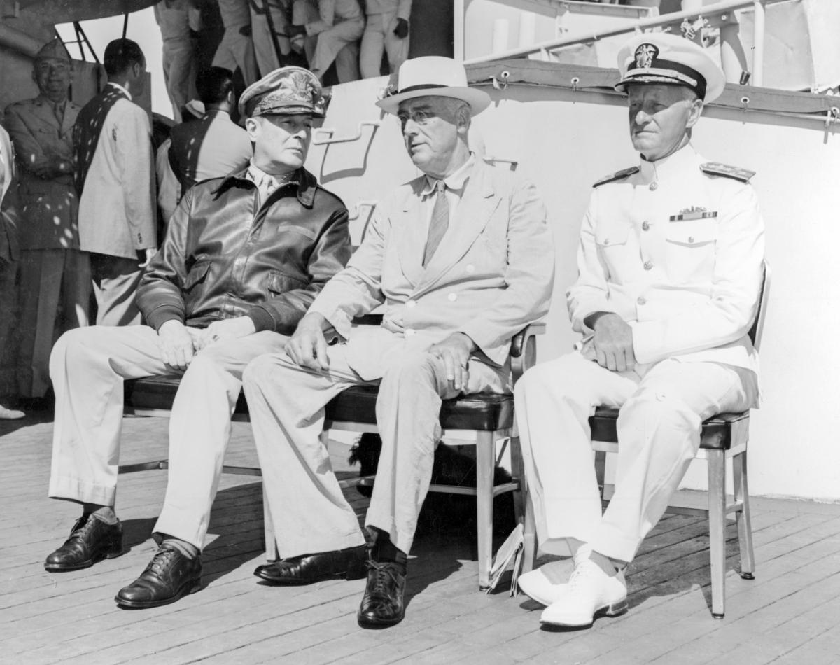 President Franklin Roosevelt sitting with General Douglas MacArthur and Admiral Chester Nimitz