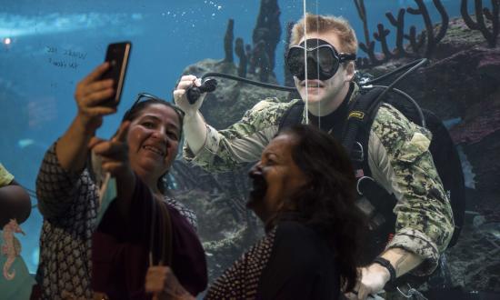 Navy Diver poses for a selfie with visitors at the New York Aquarium during Fleet Week New York 2018