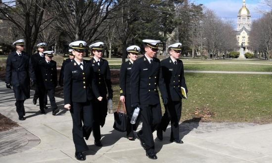 Notre Dame NROTC midshipmen walking past the iconic golden dome of the Basilica of the Sacred Heart.