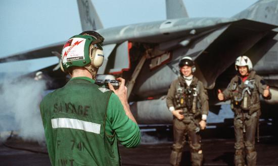 A squadron member photographs the pilot and radar intercept officer of a Fighter Squadron 74 (VF-74) F-14A Tomcat aircraft before they depart on a mission from the aircraft carrier USS SARATOGA (CV-60) during Operation Desert Storm