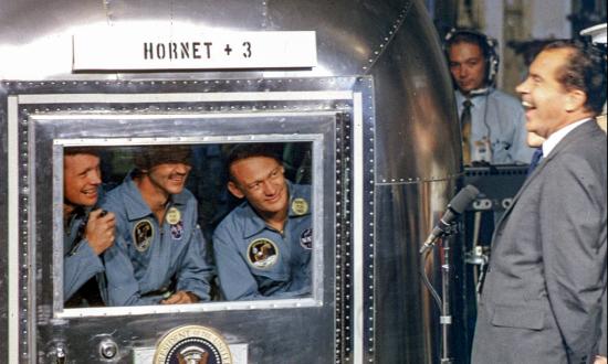 Astronauts in the Mobile quarantine facility aboard USS Hornet greet President Nixon