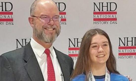 High school junior Claire Flynn, an avid participant in National History Day since she was in the sixth grade, poses with her Coskey Naval History Prize alongside  Chip Wallen, Chief Financial Officer of the U.S. Naval Institute, which now sponsors the prize.
