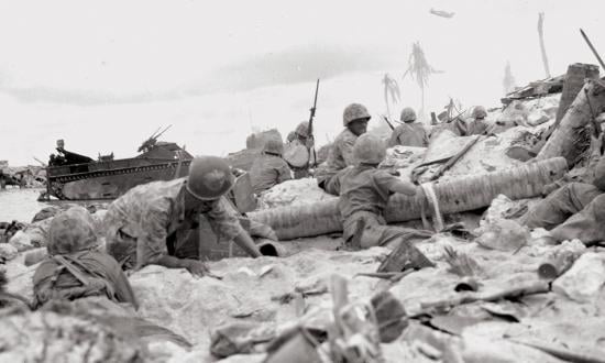 Marines on the beach at Tarawa Atoll's Betio Island duck for cover as their dive-bombers roar in overhead to blast Japanese positions, November 1943.