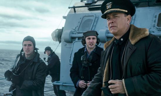 Commander Ernest Krause, portrayed by  Tom Hanks, looks seaward from the flying bridge of the fictional destroyer USS Keeling, in a scene from Greyhound. Krause has the arduous task of protecting an Allied convoy during a running battle with a U-boat wolf pack. 