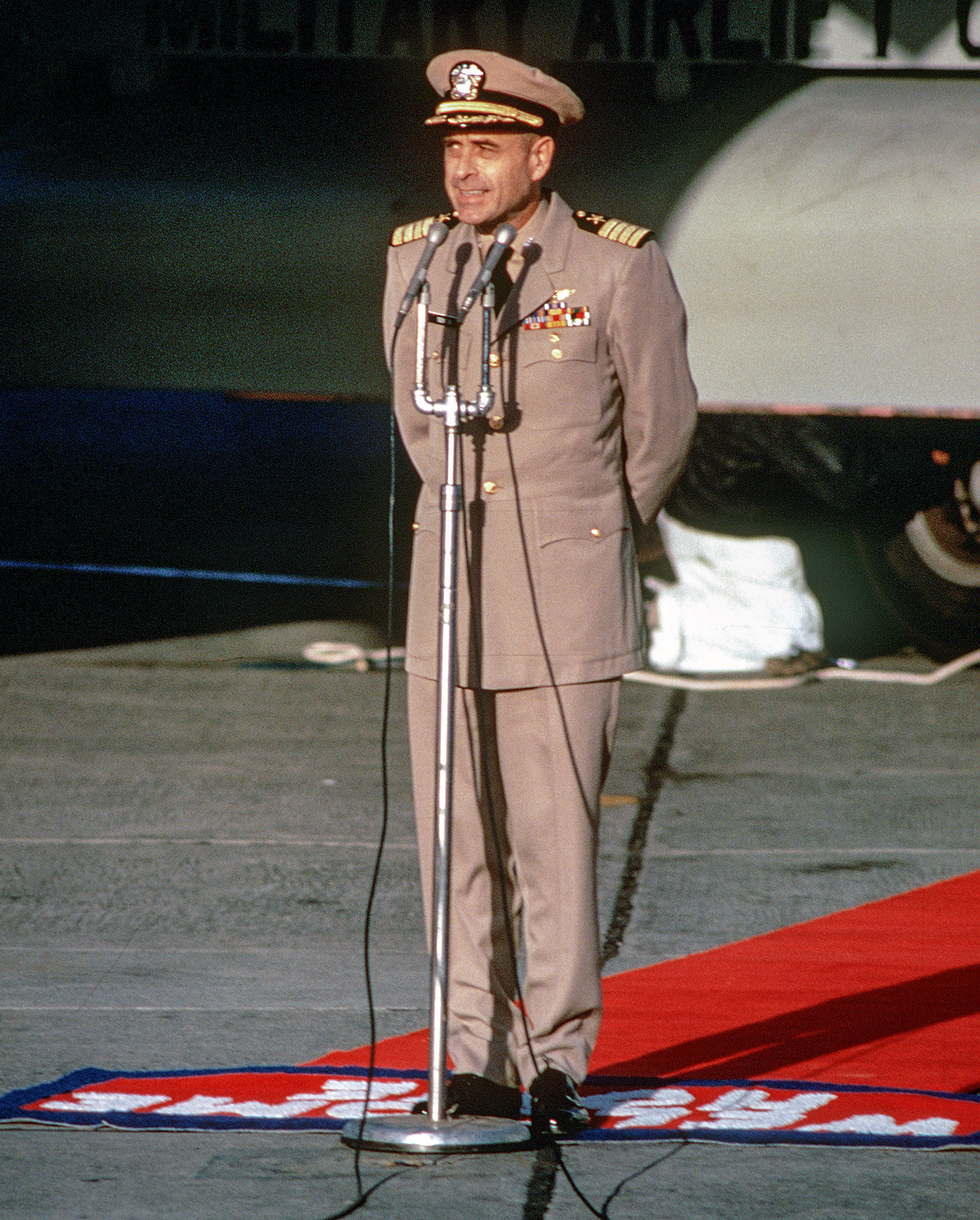 Captain Jeremiah Denton speaking in front of a C-141 Starlifter at Clark Air Base.