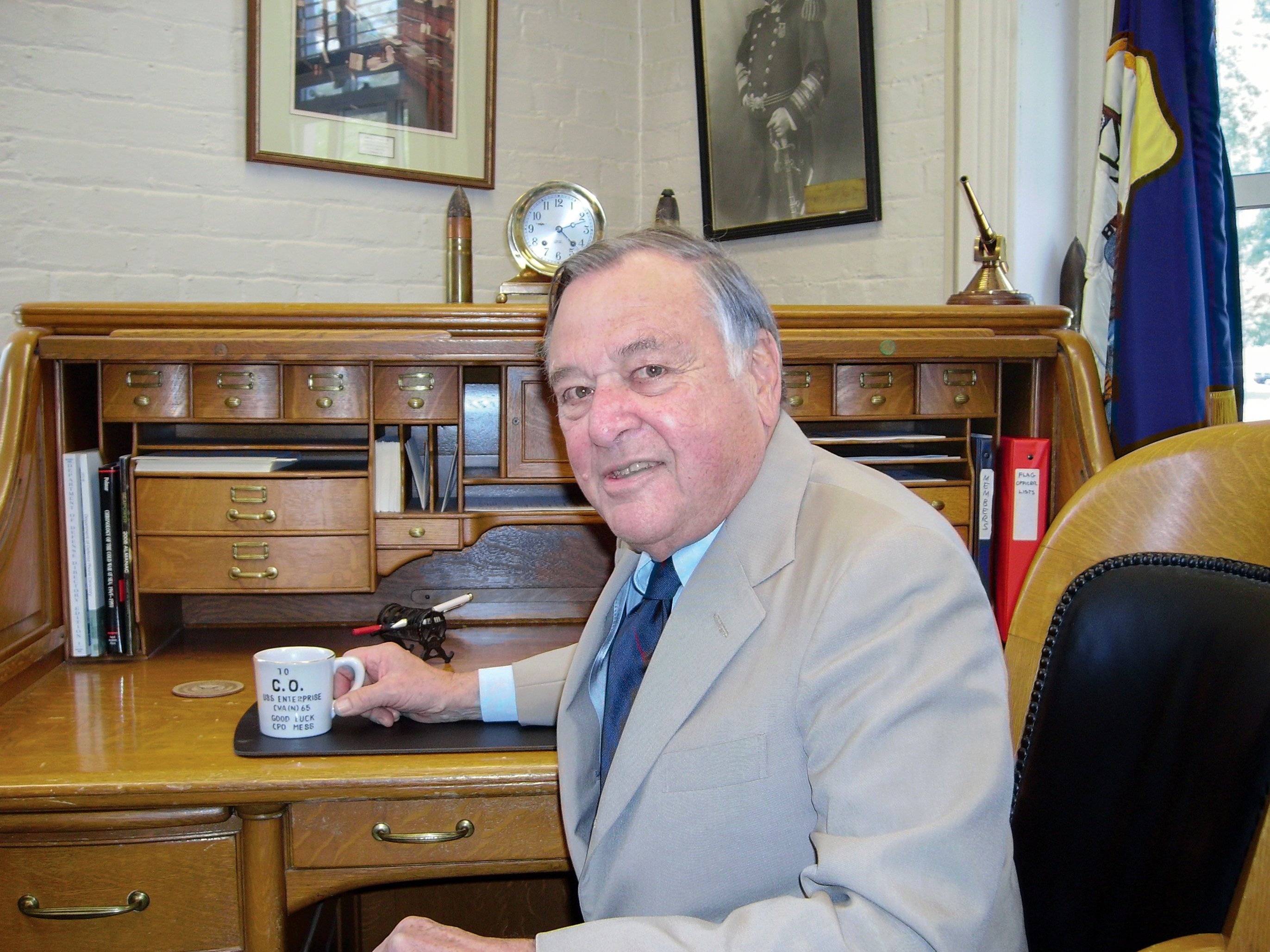 Portrait of James S. Holloway sitting at his desk holding a coffee mug