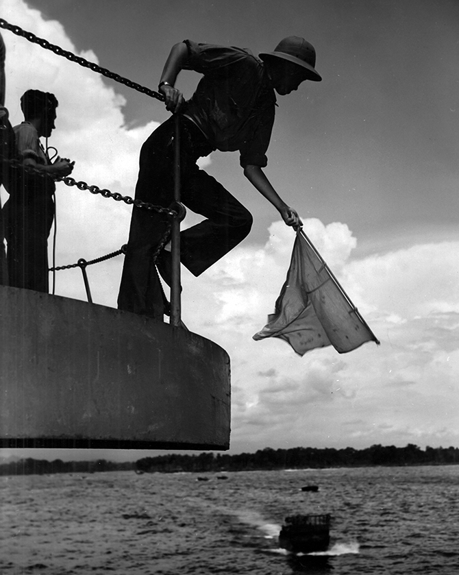 Signalman waving in an approaching boat.