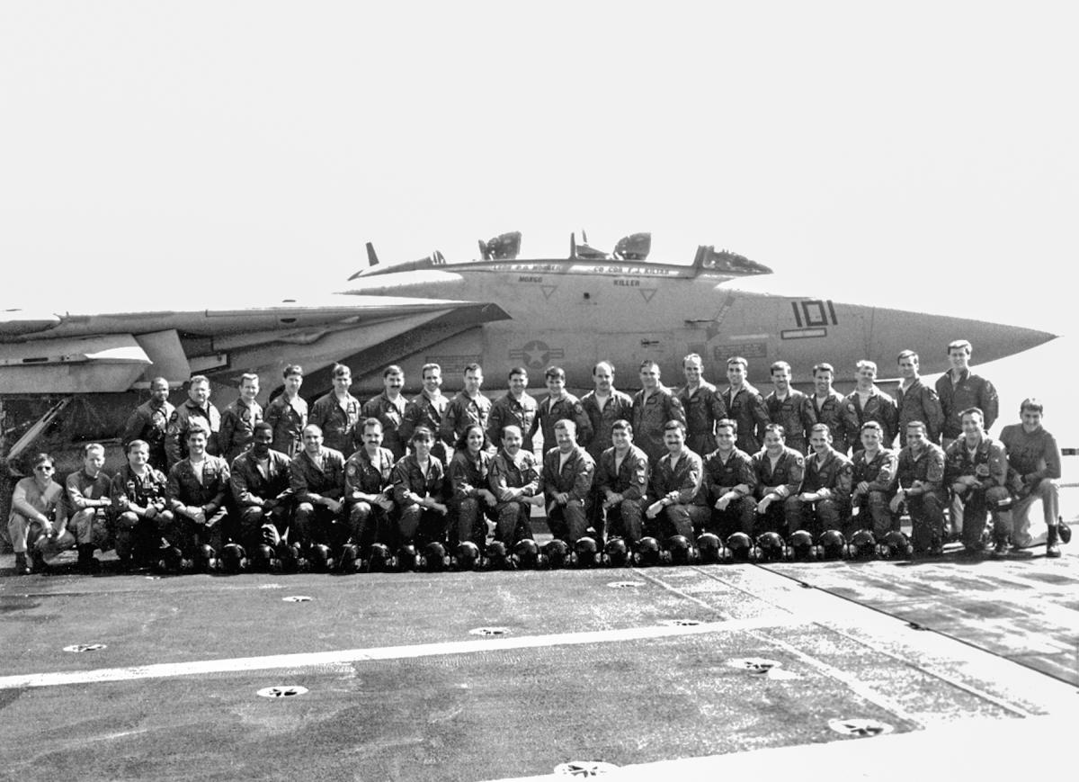 Members of VF-213 Blacklions posing in front of an F-14 Tomcat fighter aircraft