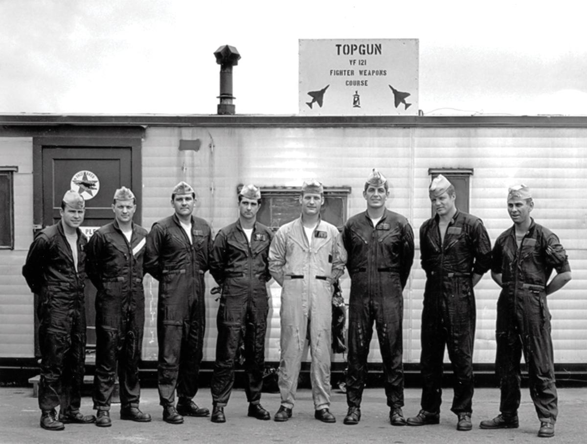 Members of TOPGUN posing in front of a trailer at NAS with sign reading TOPGUN