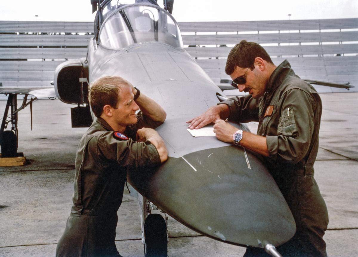 TOPGUN instructors using the nose of an F-5 Tiger II to make notes for the debrief