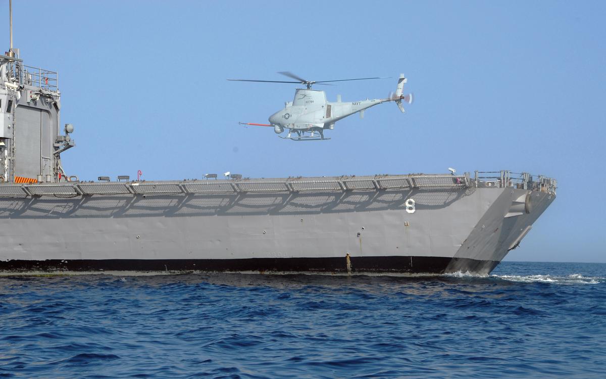 Surface port quarter view of an MQ-8B Fire Scout  hovering above the flight deck of the guided-missile frigate USS McInerney (FFG-8).