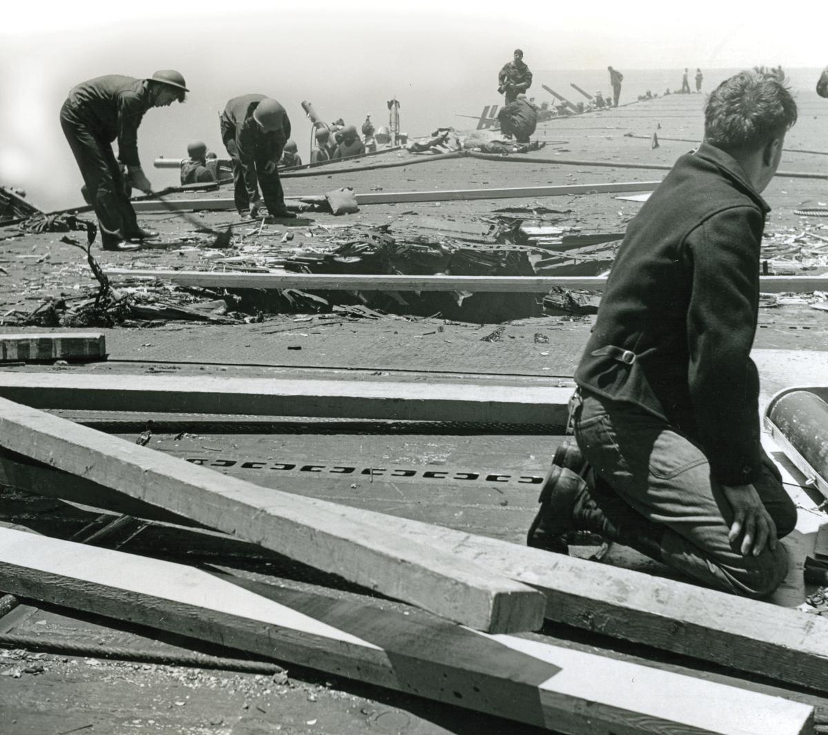 A Yorktown damage control party works to repair a 12-by-12-foot hole created by a 530-pound bomb that exploded on contact with the flight dec