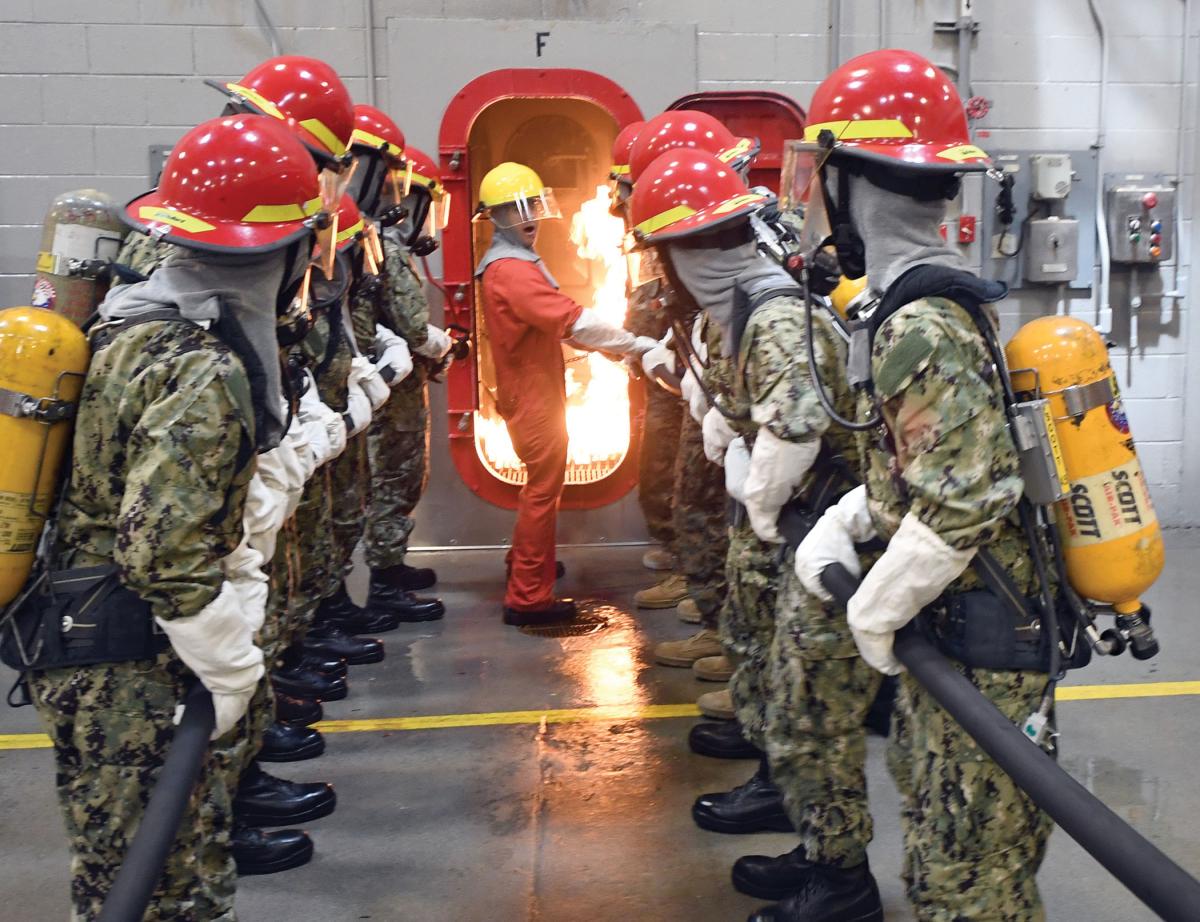 midshipman candidates fight a fire in a simulated shipboard compartment