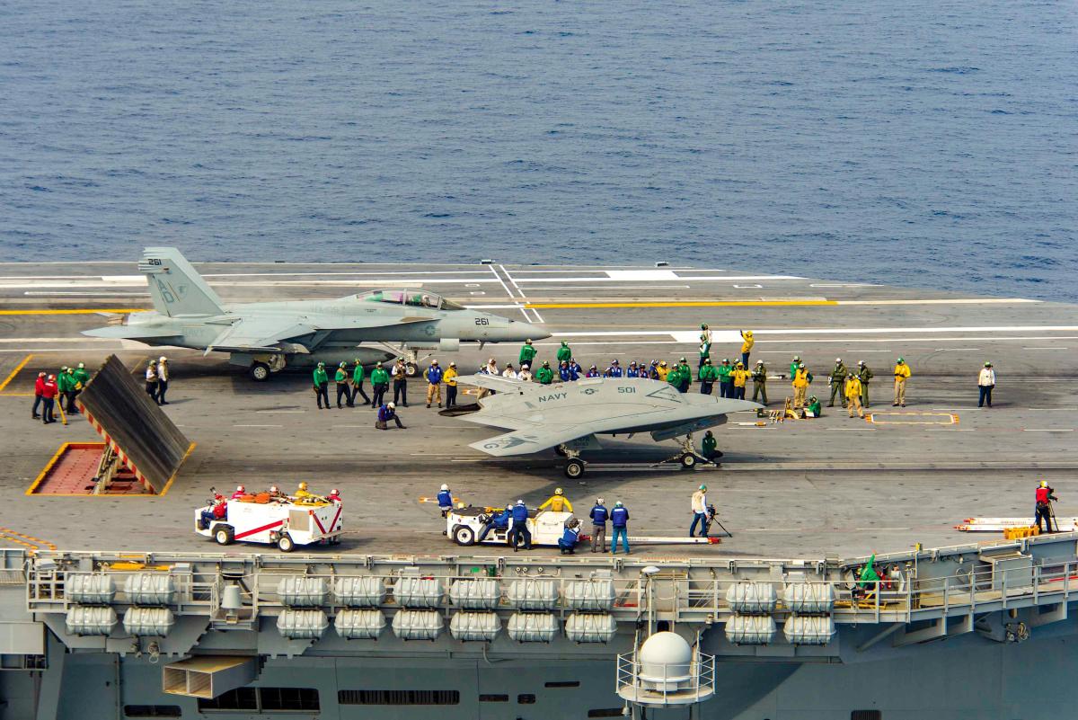 The Navy's unmanned X-47B, right, conducts flight operations aboard the aircraft carrier USS Theodore Roosevelt (CVN-71)