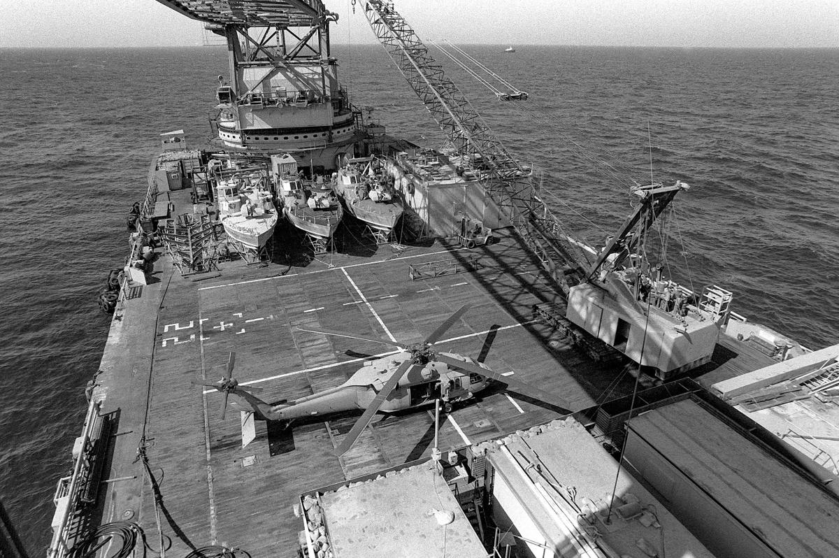 The crane aboard the barge Hercules prepares to lift a PB Mark III patrol boat into the water for a patrol.
