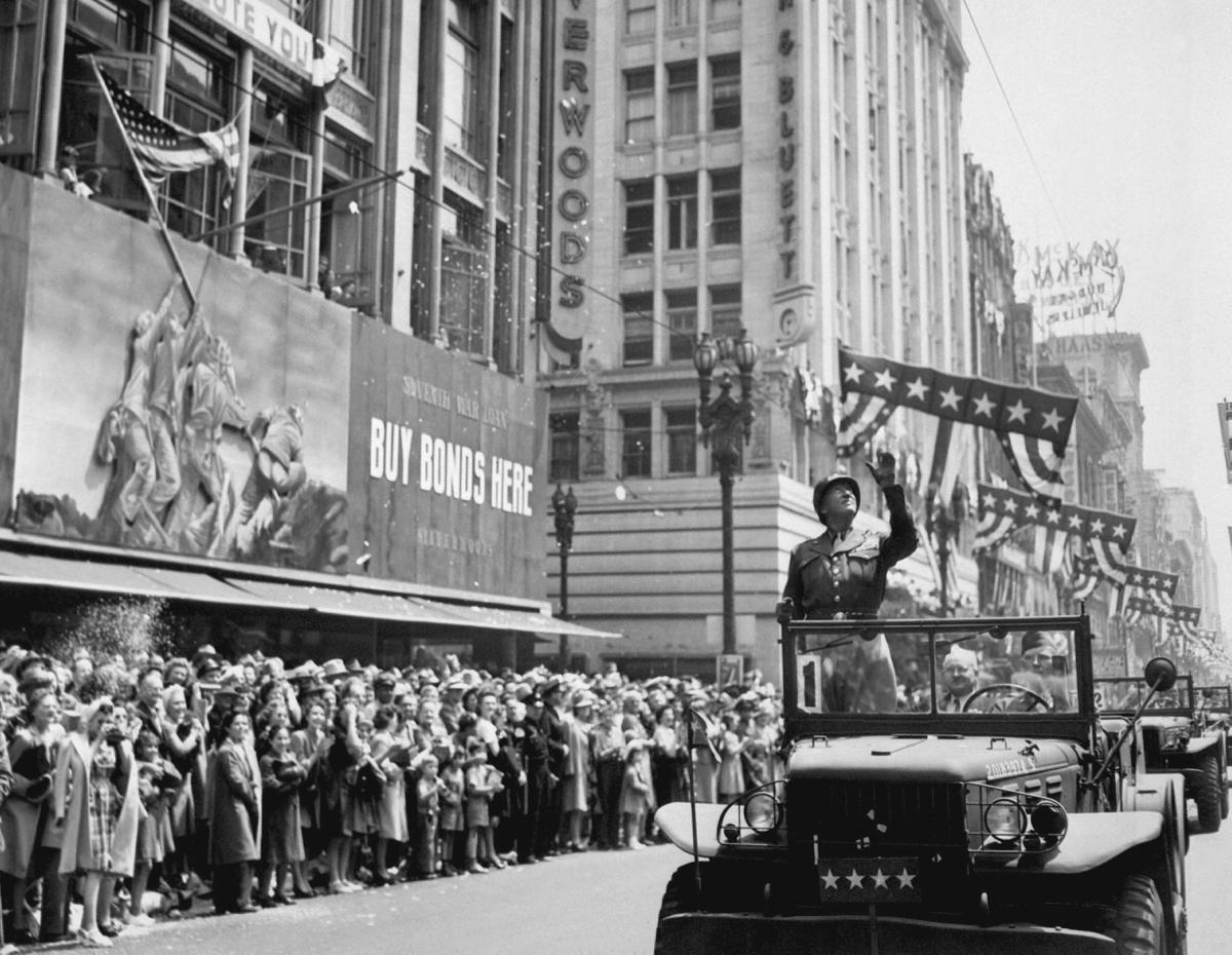 During a Los Angeles parade in June 1945, General George Patton passes a sign for the Seventh War Bond drive that features an image of the Iwo flag-raising.