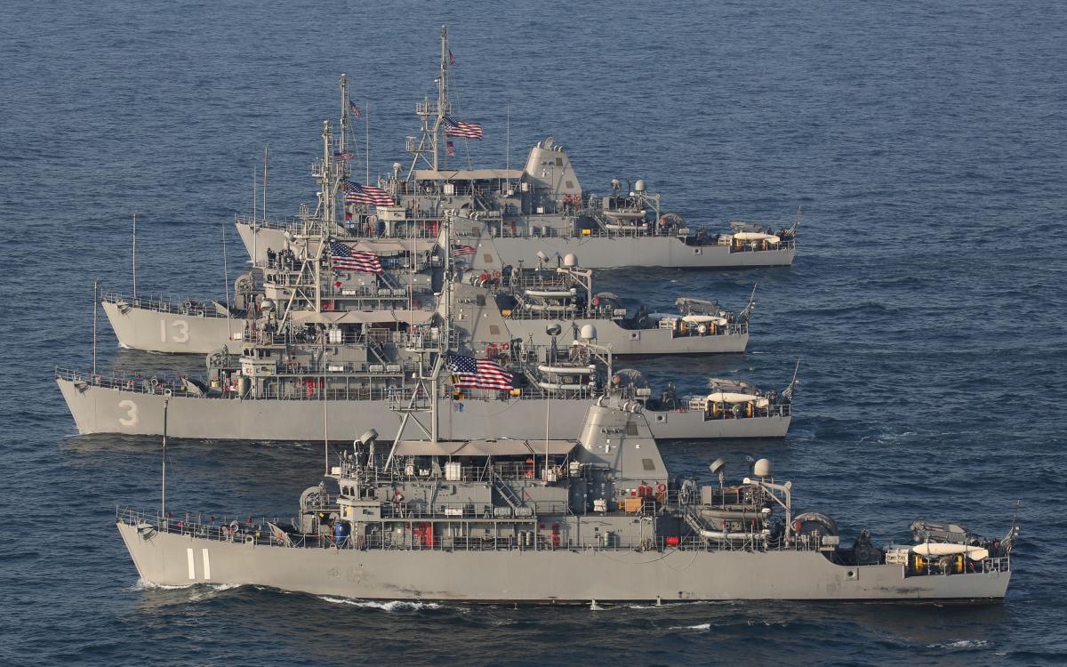 A formation of Avenger-class mine countermeasure ships maneuver in the Arabian Gulf,