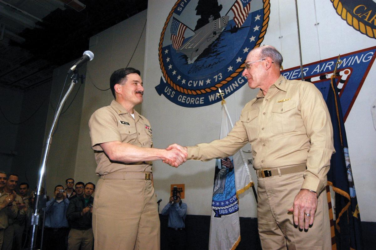 hief of Naval Operations, Adm. Vern Clark greets Master Chief Petty Officer of the Navy Terry Scott, as he prepares to address crewmembers in the hangar bay aboard USS George Washington (CVN-73).