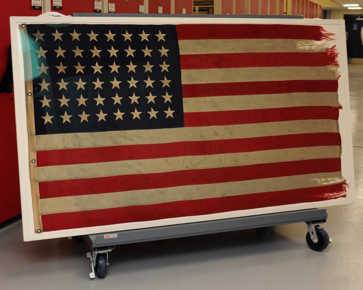 USS Taylor (DD-468) flag on a dolly in museum storage.