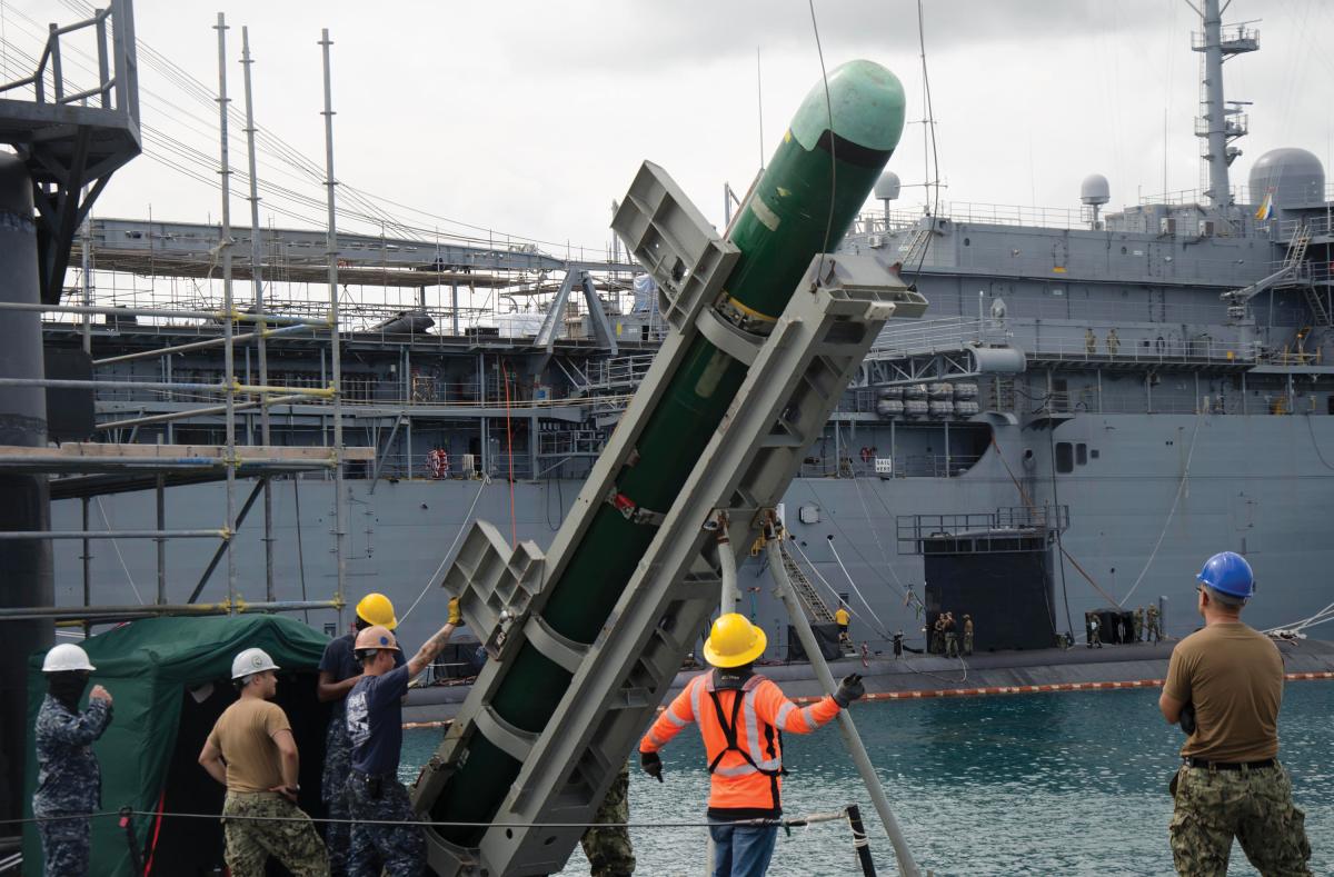 Submariners and Military Sealift Command civilian service mariners assigned to the Los Angeles-class attack submarine USS Topeka (SSN-754) secure a Mk 48 torpedo to a crane during the Topeka’s ordnance onload.