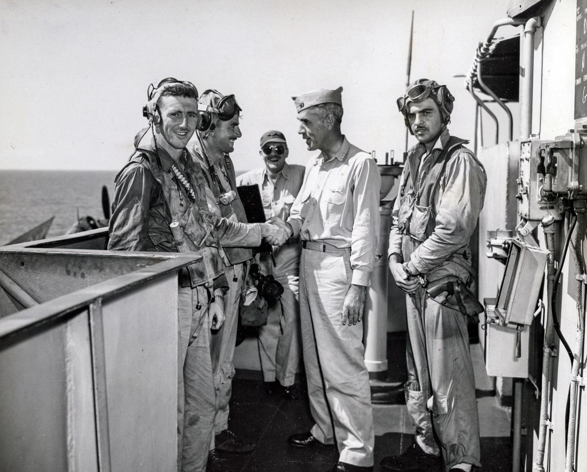 Ensign John Buchanan (left) and Lieutenant Kenneth Hippe are greeted by Captain T. B. Williamson, skipper of the USS Kalinin Bay