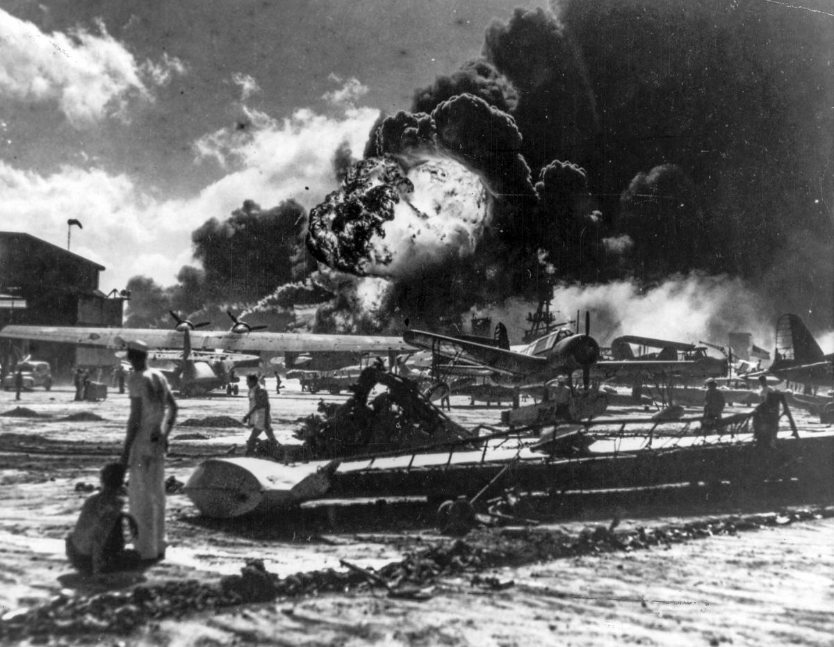 PERSONNEL WATCH BURNING PLANES AMID THE WRECKAGE OF AIR STATION