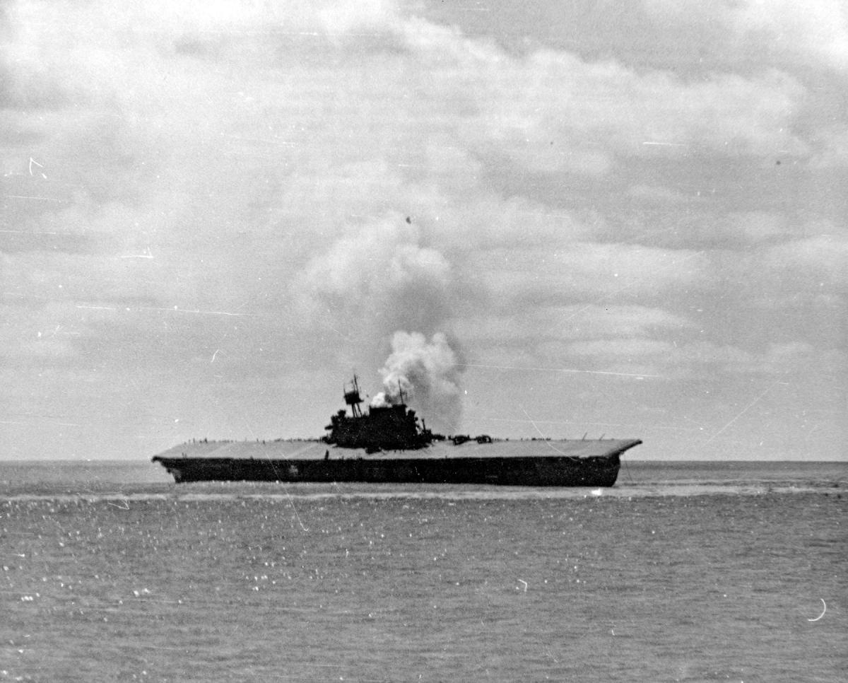 Smoke billows from sinking USS Yortown's funnel as she leans onto the port side.