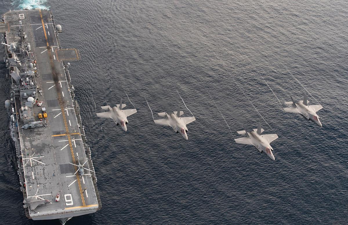 Four F-35B Lightning II aircraft fly over the amphibious assault ship USS America (LHA-6)
