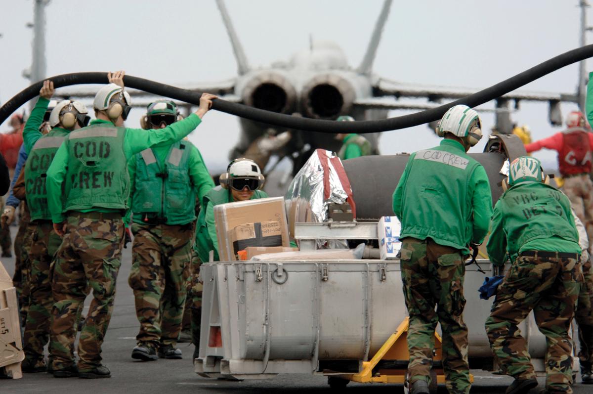 A carrier onboard delivery crew moves supplies across a carrier flight deck.