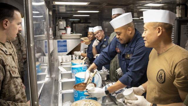 Sailors and Marines of the amphibious assault ship USS Bataan's (LHD 5) First Class Petty Officer Association Host an ice cream social for the crew on the mess decks.