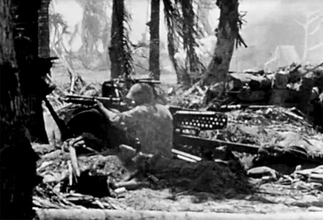 Marine sniper rests his rifle on the tire of a 37-mm gun on Betio