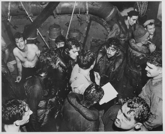 Covered with the oil of their torpedoed ship, the USS Helena (CL-50), survivors  respond to a roll  call on board the  destroyer that picked them up. On 6 July 1943, in the Battle of Kula Gulf, the Helena was hit by three  torpedoes, broke apart, and sank,  with nearly 170 of  her crew lost.