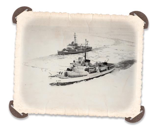 In this solid field of ice in the Bering Sea, two icebreakers try a tandem method of breaking ice. Ramming, backing, and ramming again, the vessels try forcing their way, side-by-side, in a parallel line.