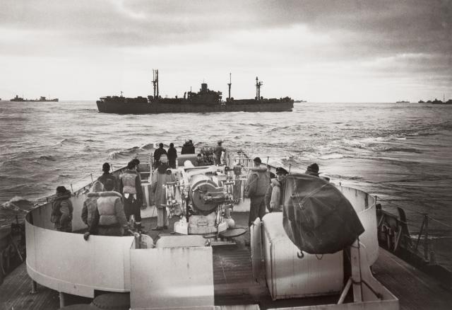 Ships of Convoy HX233 sail past the stern of the Spencer just before the cutter detects U-175 trying to break into the center of the convoy.