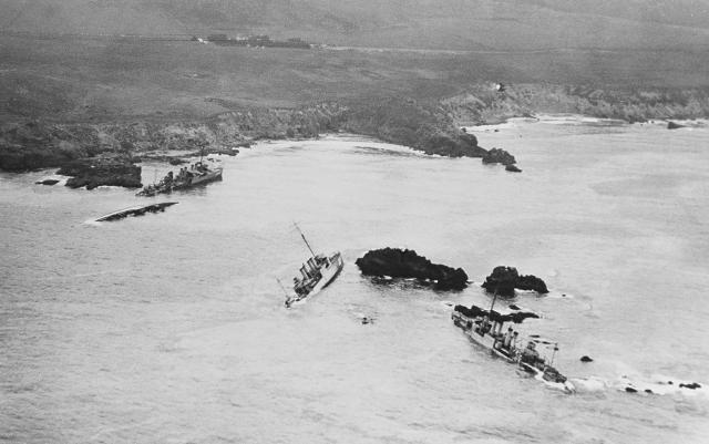 This aerial view of part of the disaster area, photographed from a plane assigned to the USS Aroostook (CM-3), shows five of the seven destroyers that ran aground: the Delphy (DD-261), capsized in the small cove at left; the Young, capsized in left center; the Chauncey, upright ahead of the Young; the Woodbury (DD-309), on the rocks in the right center; and the Fuller (DD-297), on the rocks at right.
