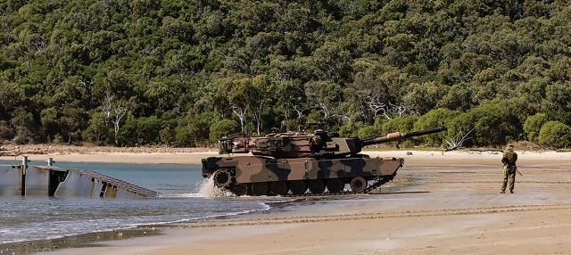 An M1A1 Abrams main battle tank leaves a mexeflote landing craft after being delivered to the beach head from HMAS Choules during Sea Raider 2023.
