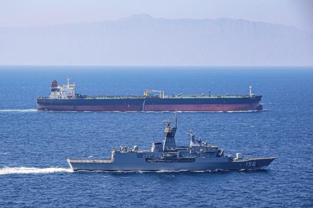 The Royal Australian Navy frigate Toowoomba escorts a merchant vessel.