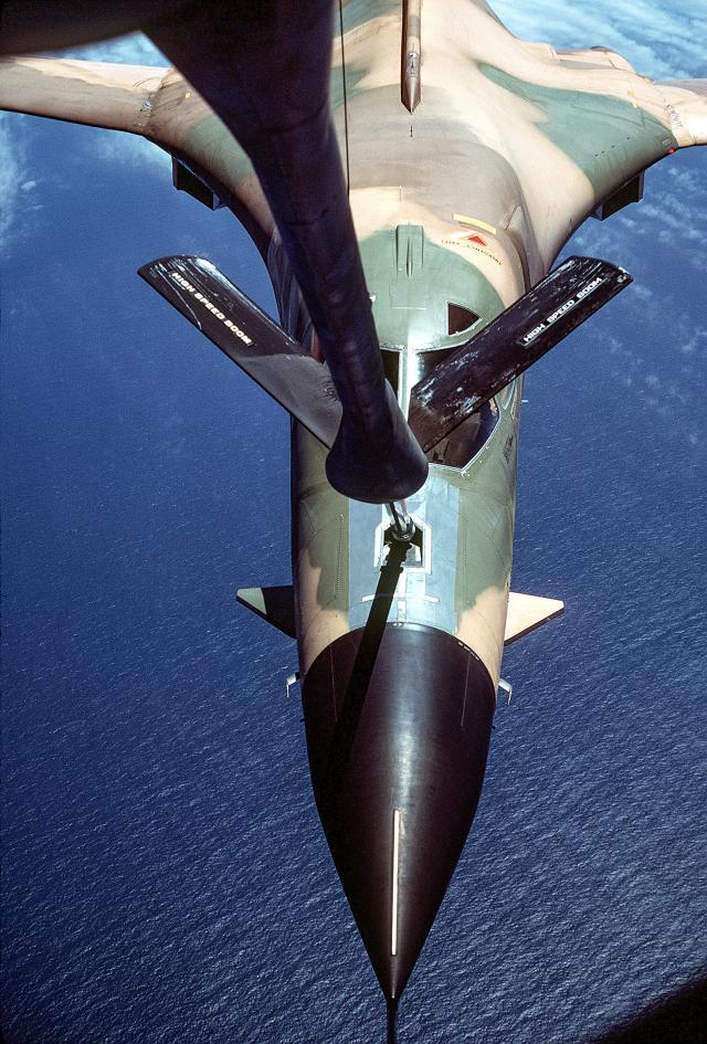 ront view of a B-1 bomber aircraft being refueled by a KC-135 Stratotanker aircraft over the water off the California coast, as seen from the boom operator's section, during testing and evaluation. 
