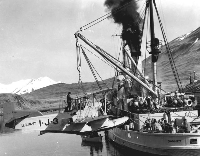 The Navy seaplane tender Gannet (AVP-8, formerly AM-41) hoists aboard an OL-9. The aircraft’s large, distinctive, centerline main float is clearly visible.