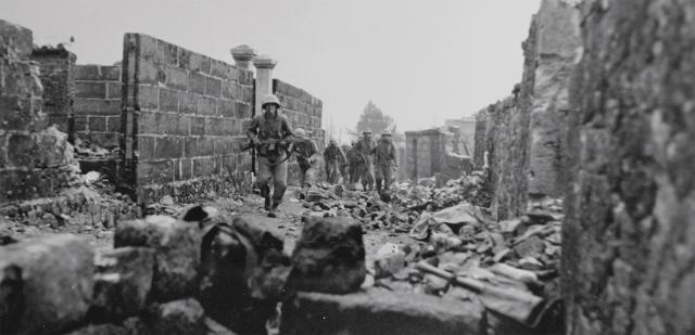 Marine patrols of the 6th Marine Division search the ruins in the city of Naha, capital of Okinawa, for Japanese snipers.