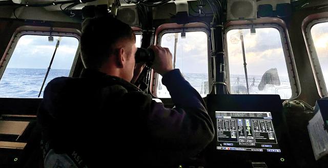 A Coast Guard officer looks out from the bridge of the USCGC Myrtle Hazard (WPC-1139) during a search-and-rescue operation near Guam in March. Watchstanding on board FRCs is highly demanding, with just two bridge watchstanders fulfilling the responsibilities of five on board a similarly equipped medium-endurance cutter.